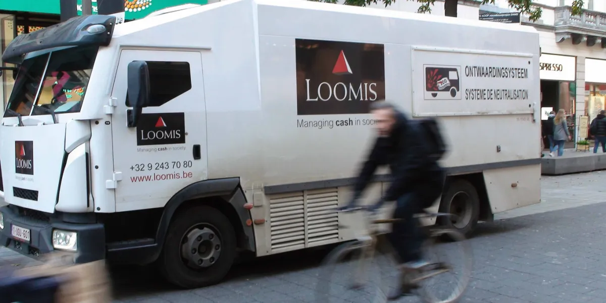 scene of retail store, advertising sign, people, loomis managing cash in society land vehicle during the day at antwerp city shopping district in belgium europe