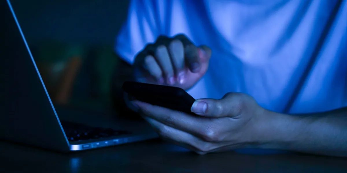 close up young man hand holding smartphone for access by unlock on screen and for register website on internet in the late night at dormitory , internet addiction concept