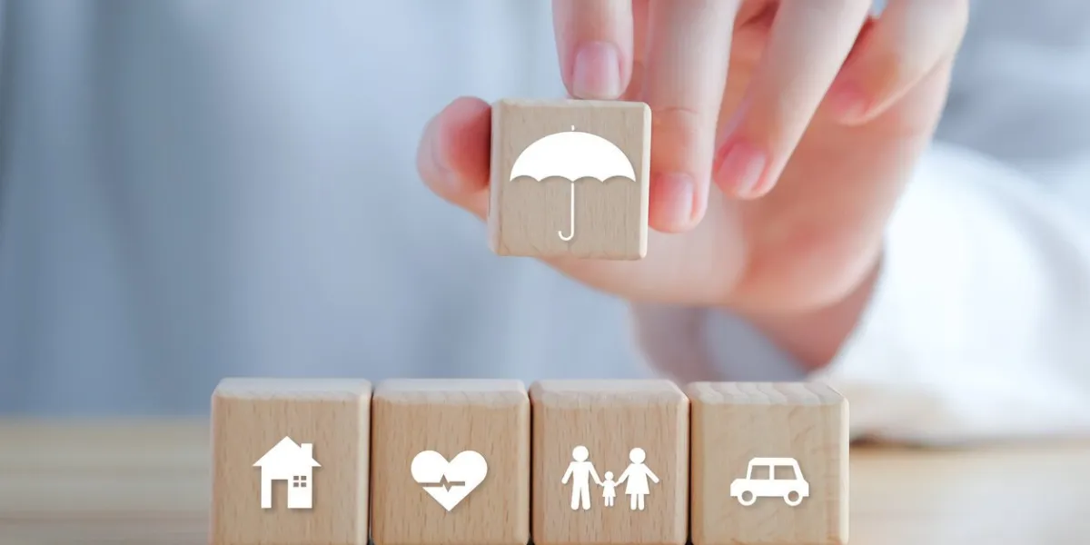 insurance concept protection against a possible eventuality hand holding umbrella icon and house, car, family and health icon on wooden block for assurance life concept