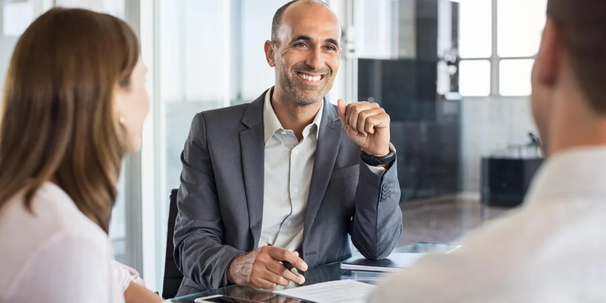 mature financial agent in meeting sitting with young couple happy consultant talking with couple about their savings plan insurance advisor in a meeting with man and woman