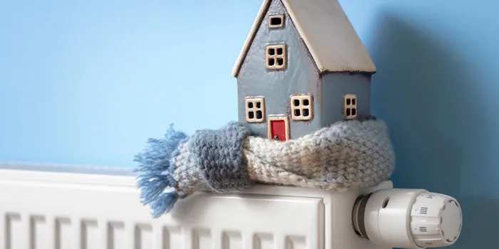 house model wrapped in scarf on radiator home winter heating and insulation background fuel and energy crisis concept