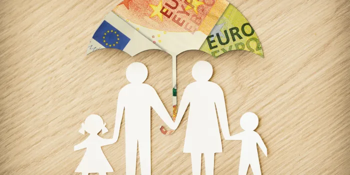 paper family silhouette with umbrella made of euro banknotes on wooden background - concept of family financial protection