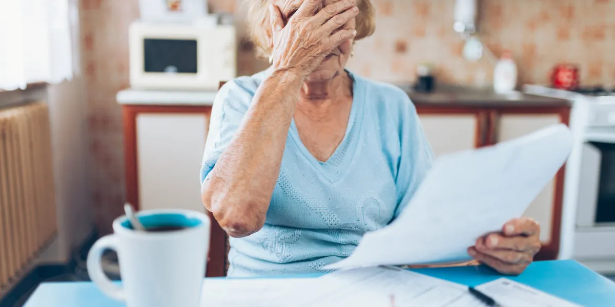 elderly woman looking at her utility bills and paperwork