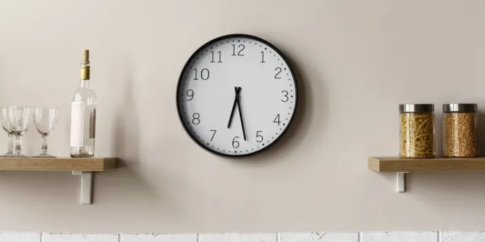 round wall clock between wooden kitchen shelves showing time