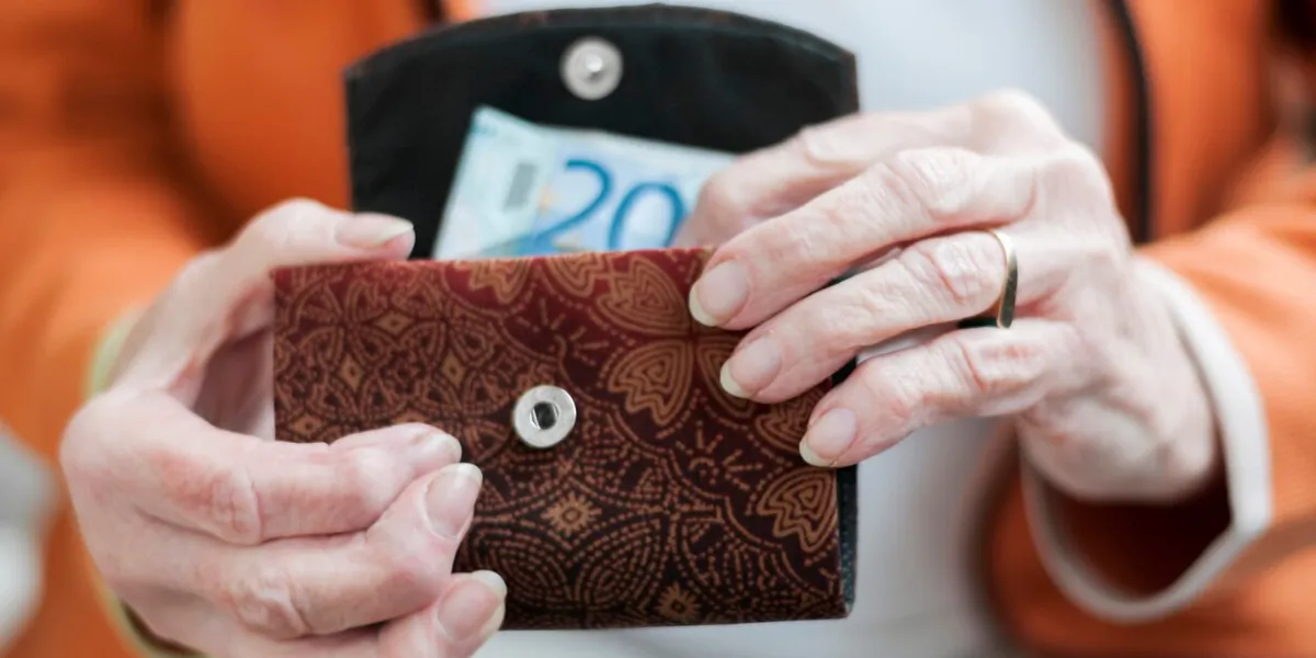 senior women looks in her purse with euro banknotes