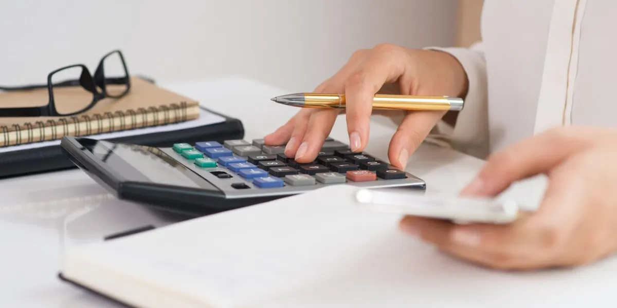 closeup of woman using calculator and smartphone person calculating data and browsing on device technology concept cropped view