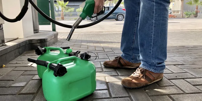 man filling plastic fuel cans at a petrol station