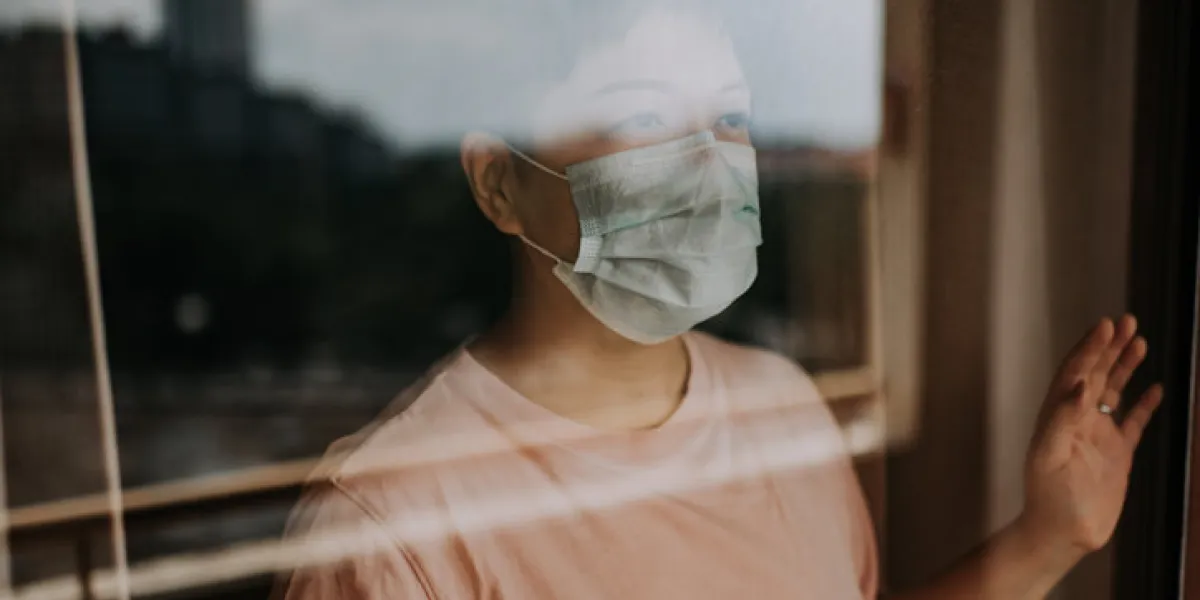 an asian chinese female looking out from her balcony window with her face mask during the restricted movement order in malaysia
