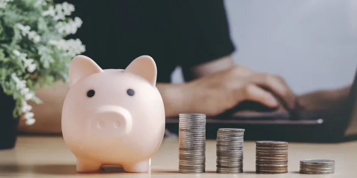 saving money wealth and financial concept asian men working at home during the crisis are calculate family income and expenses, along with pension coins and piggy banks on wooden floors