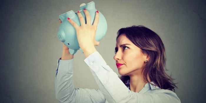 young worried woman with empty piggy bank