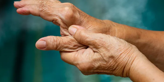 trigger finger, senior woman's left hand massaging her thumb finger, suffering from pain, close up & macro shot, swimming pool background, office syndrome, healthcare and massage asian body concept