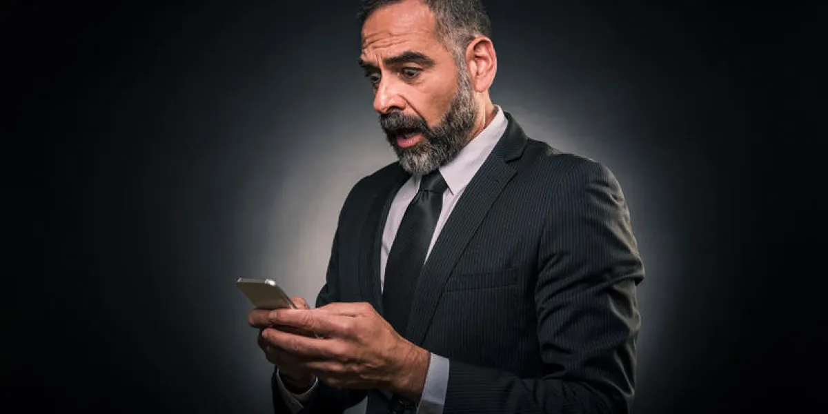 shocked senior business man receiving bad news on his phone