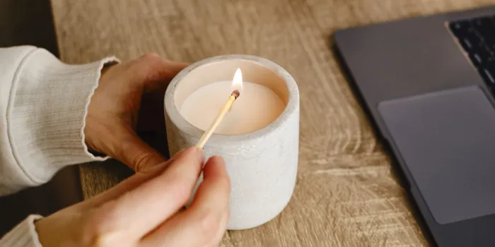 the girl lights a candle at her desk at home a minute of relaxation after working with a laptop relaxation and zen atmosphere