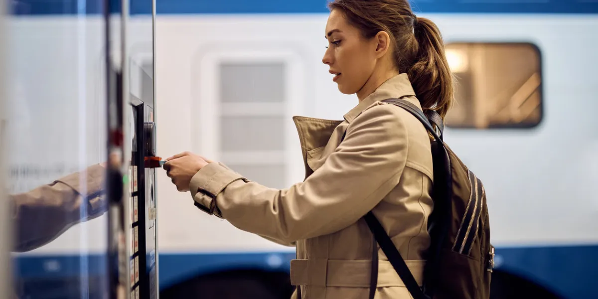 female passenger buying train ticket at automatic ticket machine at the station