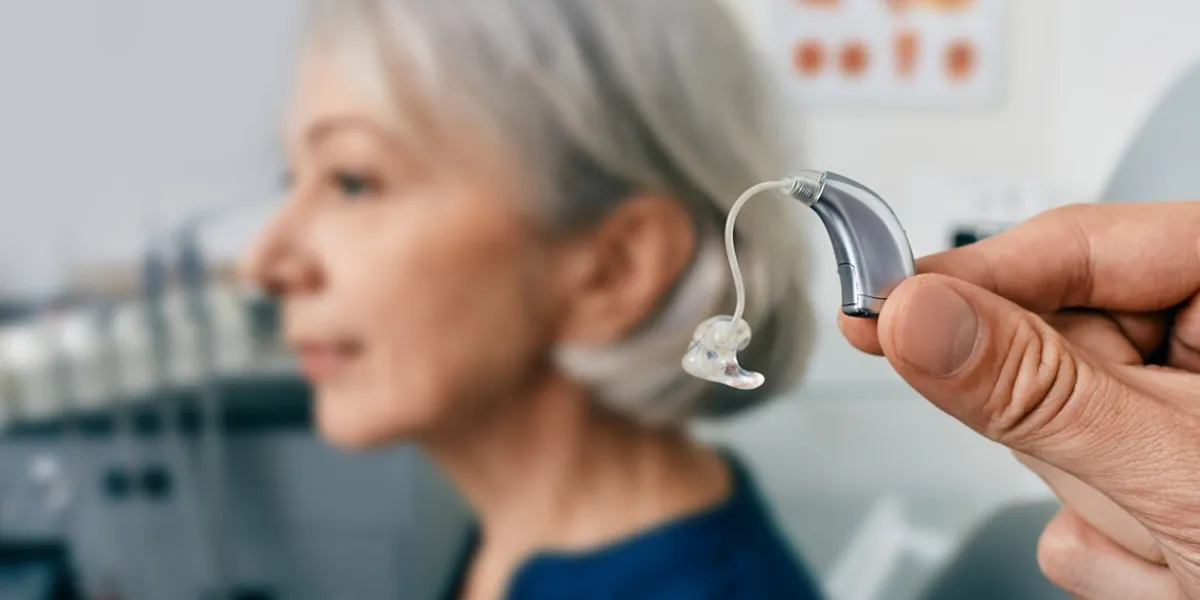 close-up of hearing aid near senior patient's ear at audiology clinic hearing solutions, hearing bte aids