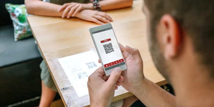 unrecognizable man scanning restaurant menu qr code on table