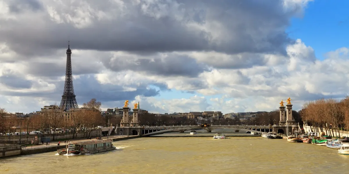 tourist boat at the seine in paris with the eiffel tower in the background on a cloudy winter day