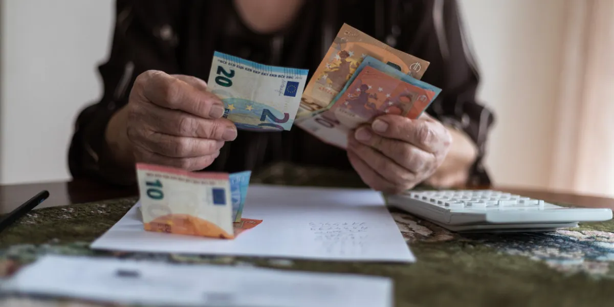 finances, savings, annuity insurance and people concept - senior woman with calculator and bills is counting money at home senior woman is calculating taxes at homecounts the pension