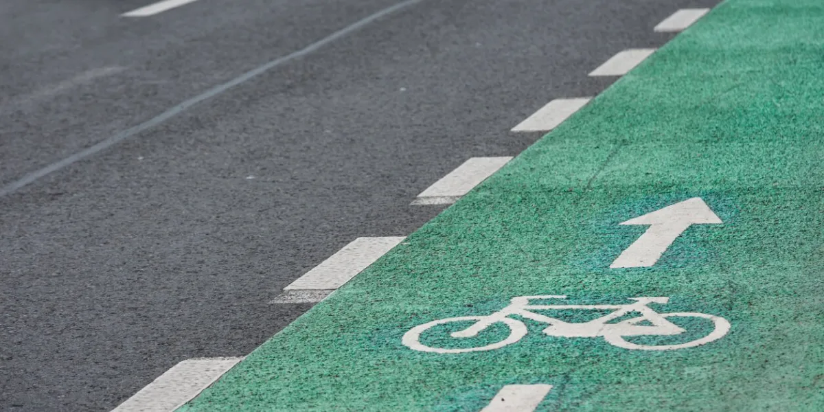 bicycle road mark on a green lane next to car lane sectioned by a disrupted white line