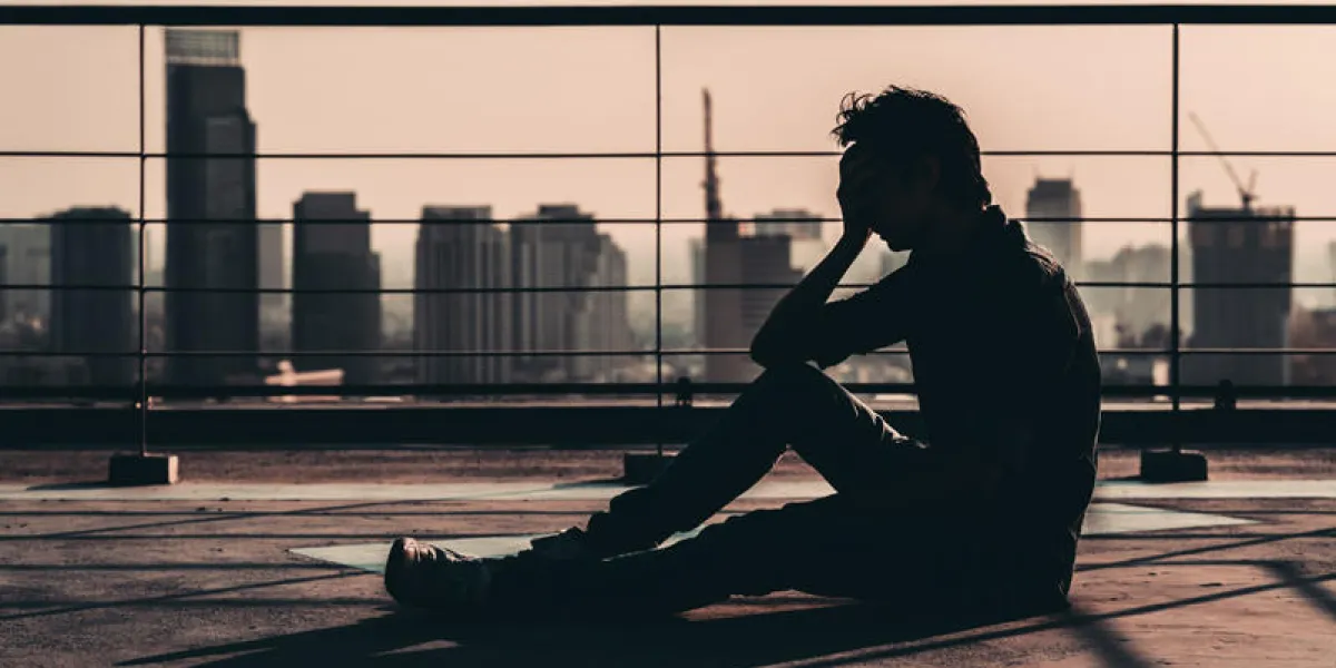 silhouette of sad depressed asian man lost hope and cry, sit on building rooftop at sunset, dark mood tone concept of major depressive disorder, friend zone, unemployment, stress emotion or paranoid