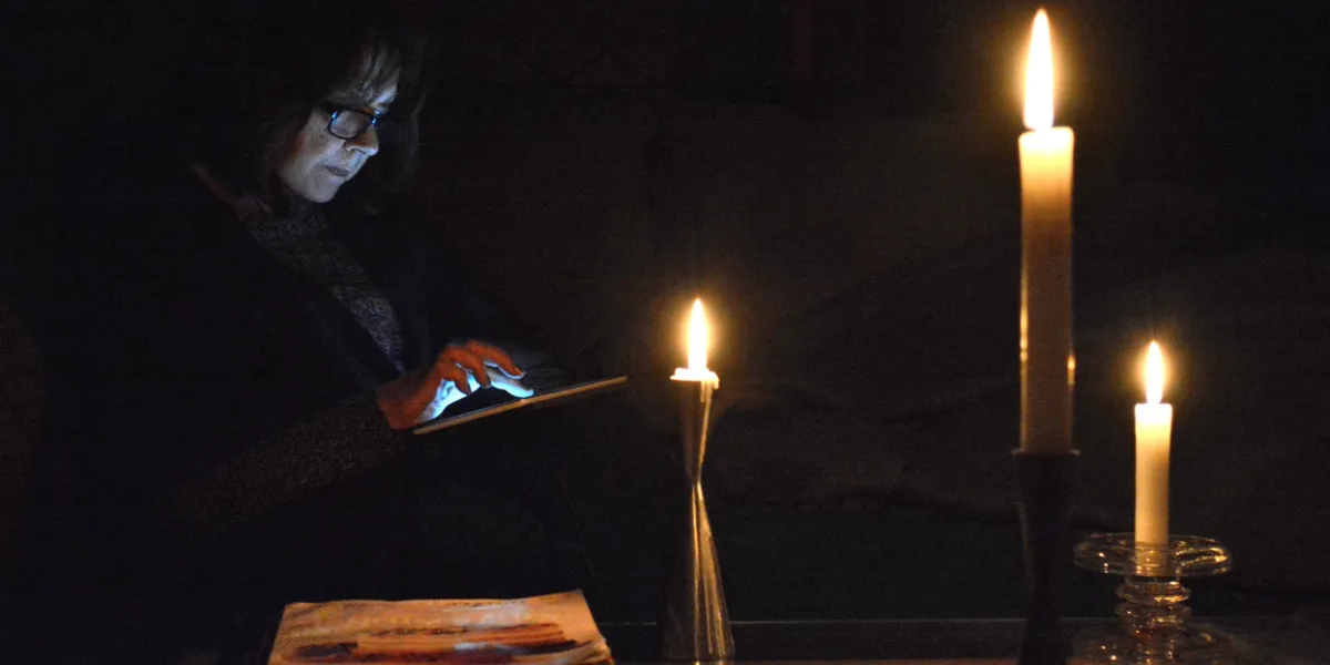 lifestylethis moody, dark, image shows a woman reading by candle light on her digital tablet, while awaiting the return of power to her home, after a widespread power outage