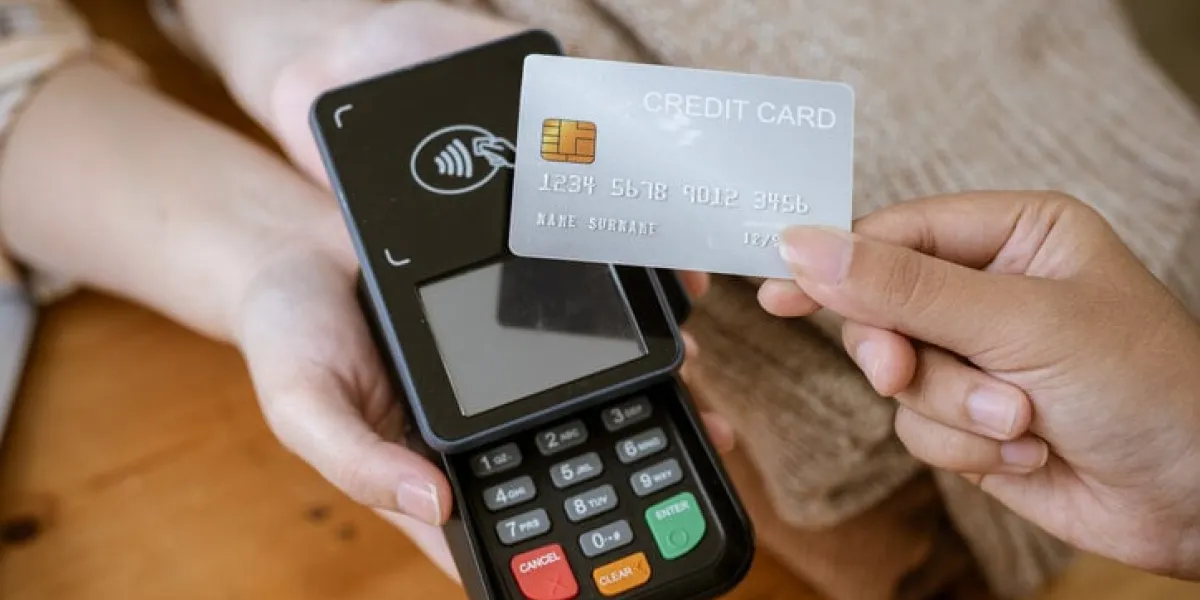 a close-up image of a customer tapping her credit card with a payment terminal or credit card machine at a cashier in a clothing store cashless payment, card reader, electronic funds transfer