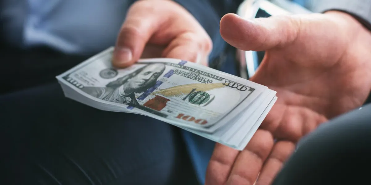 our business influential wicked businessman sitting next to another businessman and giving him a bribe