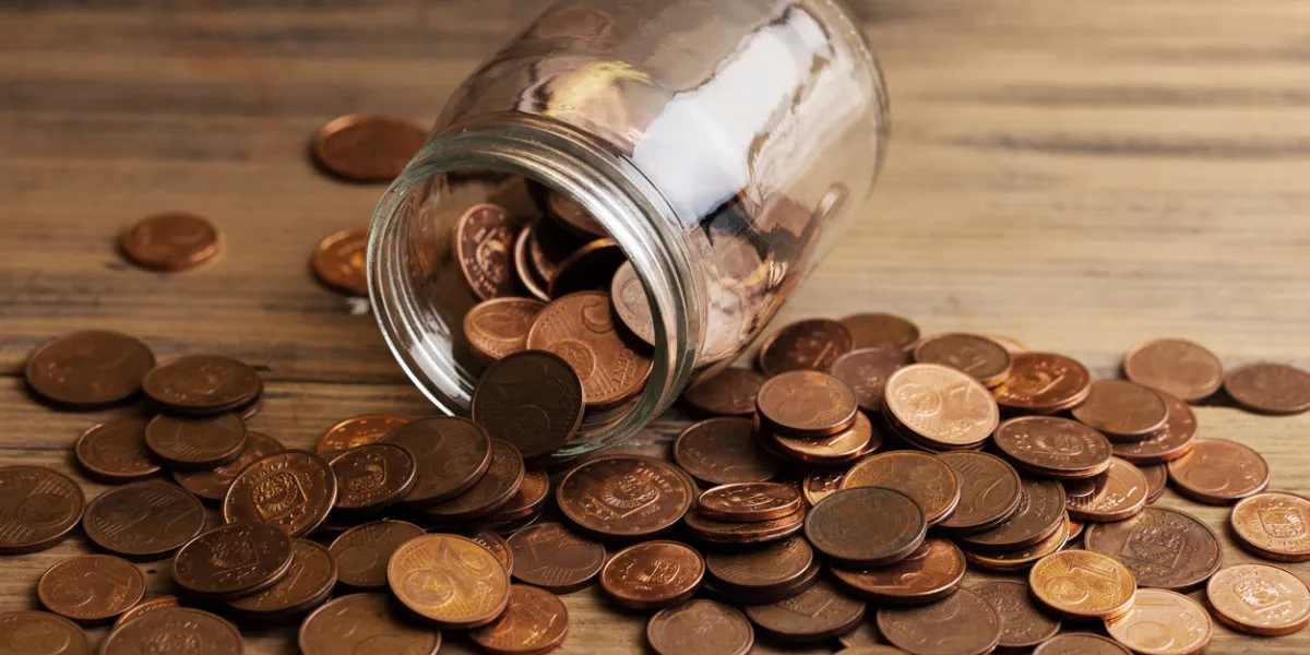 closeup shot of a shiny copper low value euro coins spilled from a glass jar