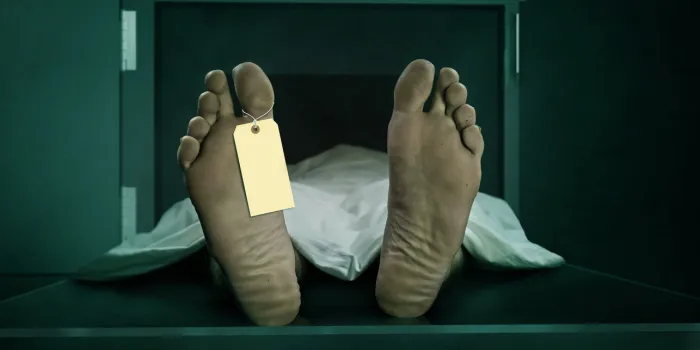 male human body lying dead at morgue capsule with blank identification label close up foot of man cadaver covered with sheet having indentity tag on toe in human life loss and death concept