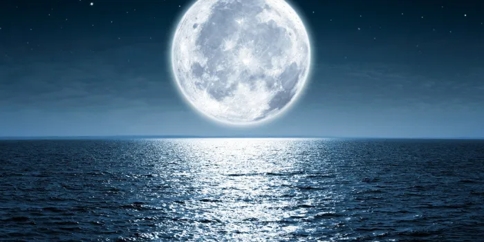 full moon rising over empty ocean at night with copy space