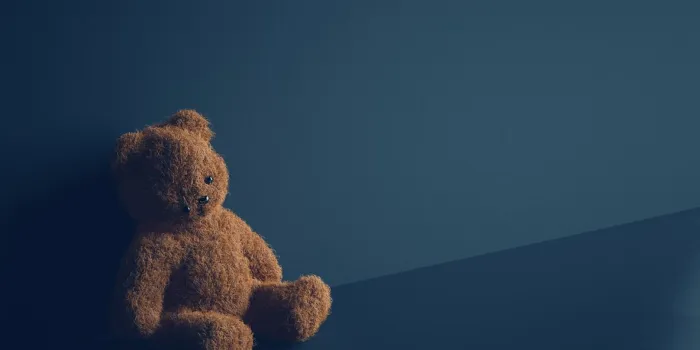 teddy bear with torn eye sits in dark room child abuse and violence concept