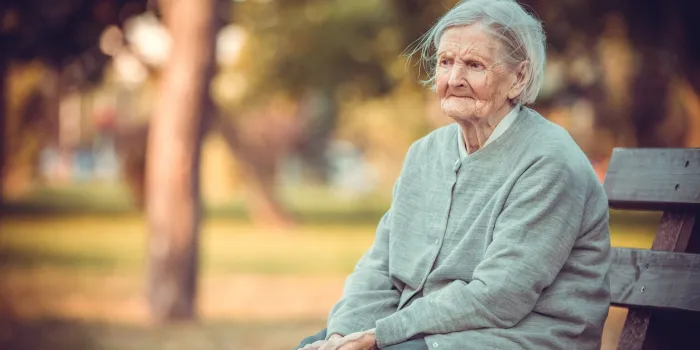 portrait of senior woman sitting on bench in autumn park old lady feeling lonely and sad frustrated aged female outdoors