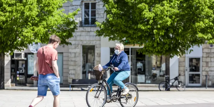chartres, france - april 18, 2020  unidentified aged woman with a protective mask riding her bike on her way back to home after shopping for food during the lockdown time due to coronavirus crisis in
