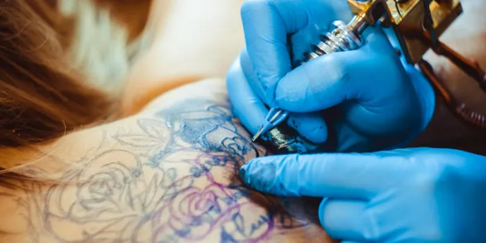 tattooer showing process of making a tattoo, hands holding a tatoo machine