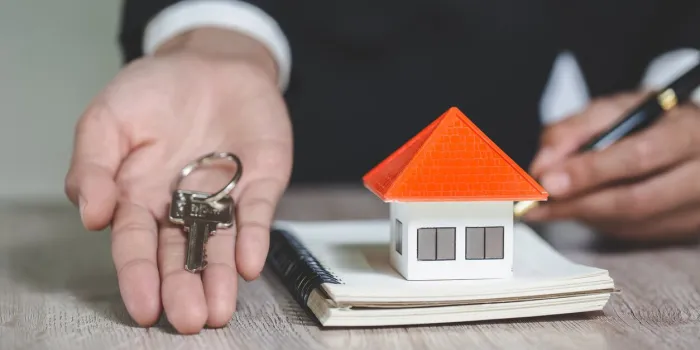 real estate agent holding house key to his client after signing contract agreement in office,concept for real estate, renting property