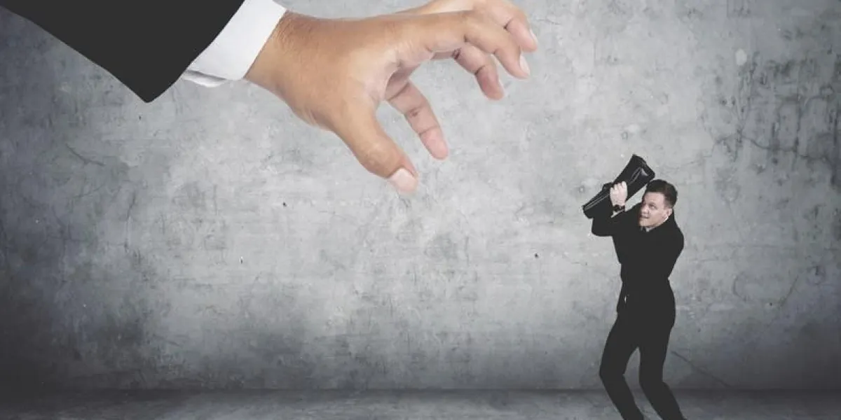 terrifying businessman covering his face being attacked by a giant hand