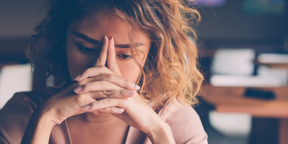 closeup of sad young asian woman at cafe leaning head on clasped hands and staring into vacancy tired freelancer feeling burnout stress and bad news concept