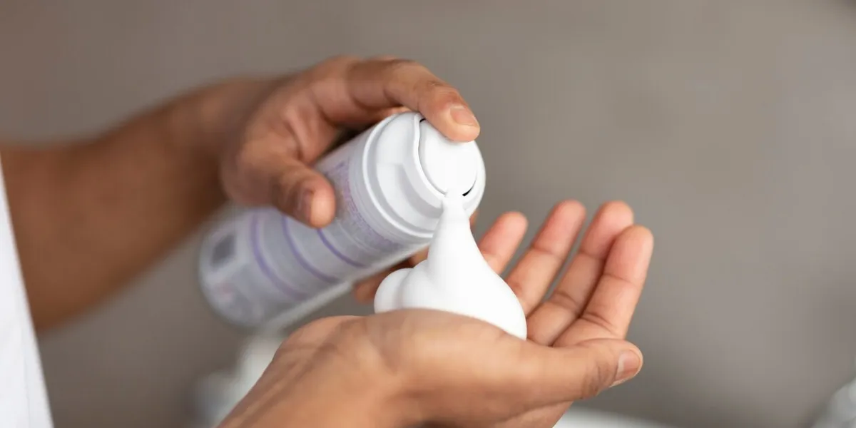 unrecognizable man applying shave foam on hand, standing in bathroom and preparing for shaving, closeup guy making morning beauty routine at home