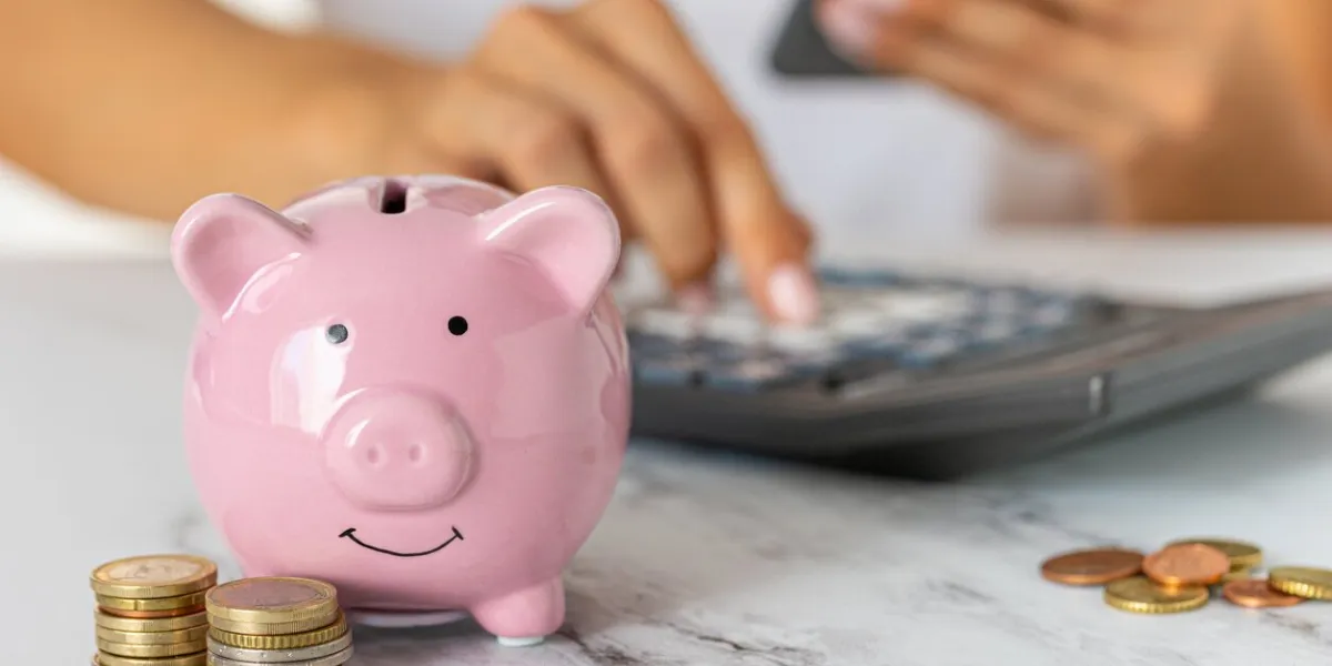 close-up of a woman's hands counting expenses on a calculator with a piggy bank on an office desk economy, crisis and inflation cost management