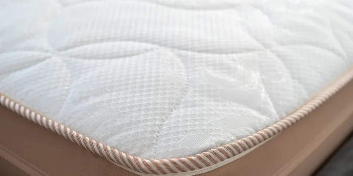 close up view of comfortable and soft topper on white orthopedic memory foam mattress in store concept of choosing bed in store advertising of healthy sleeping at bedroom