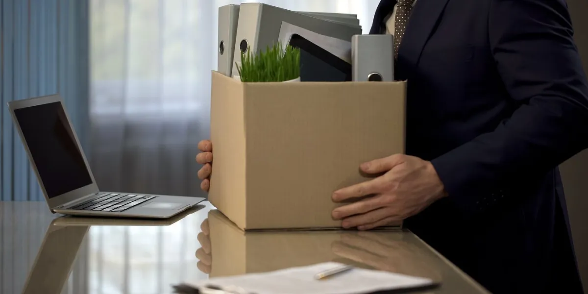 employee putting his stuff from work desk in carton box, leaving job, retirement