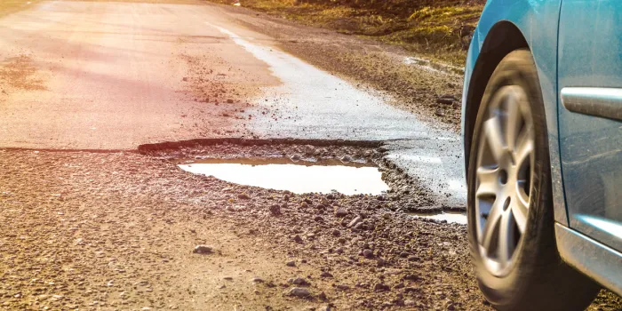 car and winter pothole on open road
