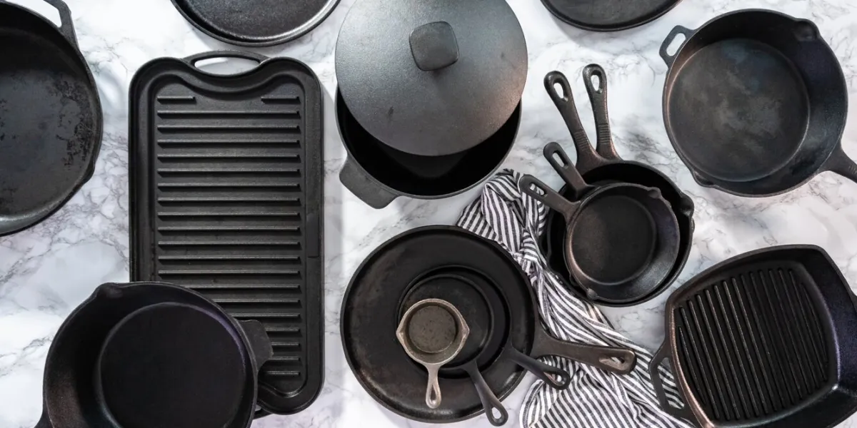 flat lay variety of cast iron frying pans on a marble background