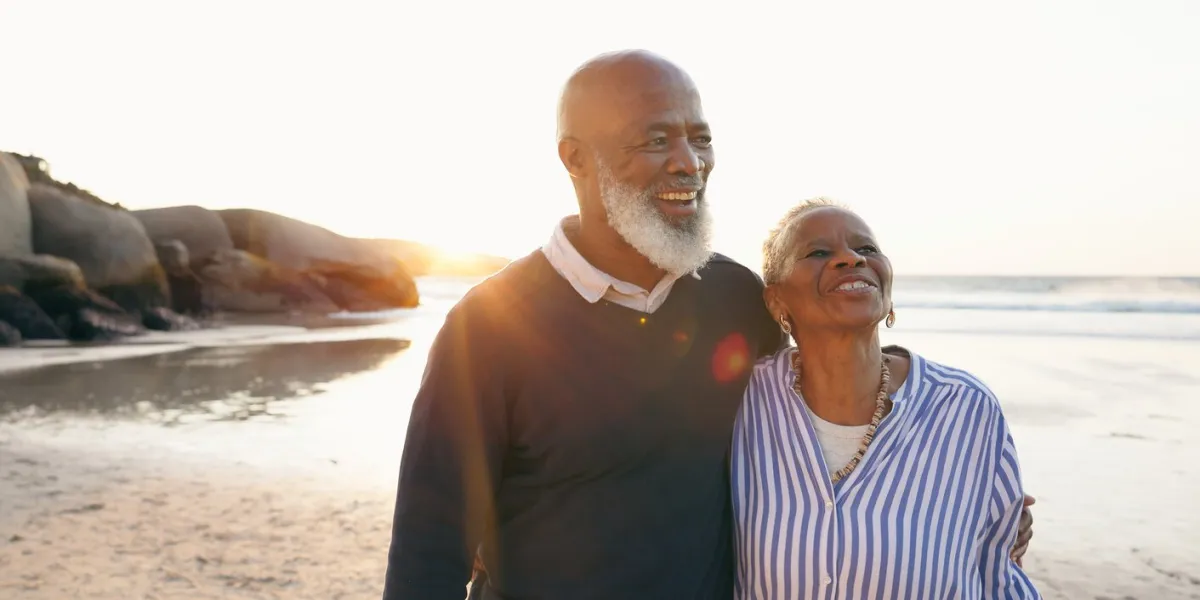 senior couple, smile and hug by ocean, love and bonding on vacation, holiday and trip to beach happy black people, embrace and support or trust, commitment and connection in marriage or retirement