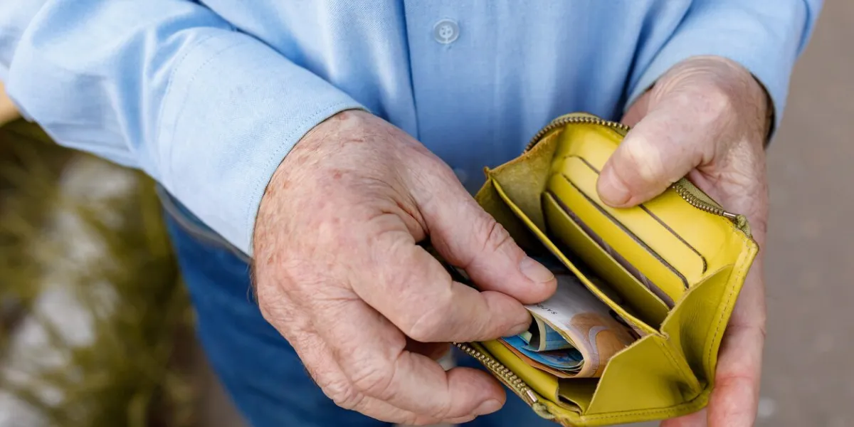 senior man looks in his purse with euro banknotes old man puts euro bills in his wallet a wallet with the last money in the hands of an elderly man a pensioner counts out the rest of his pension