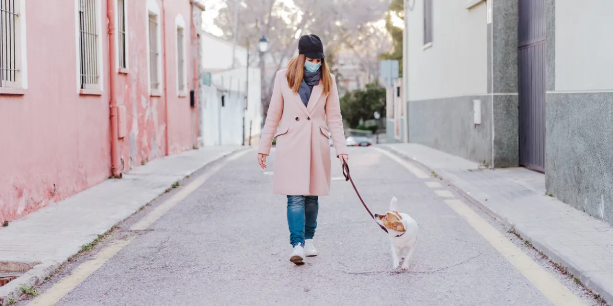 caucasian woman in the street wearing protective mask and walking with her dog corona virus concept