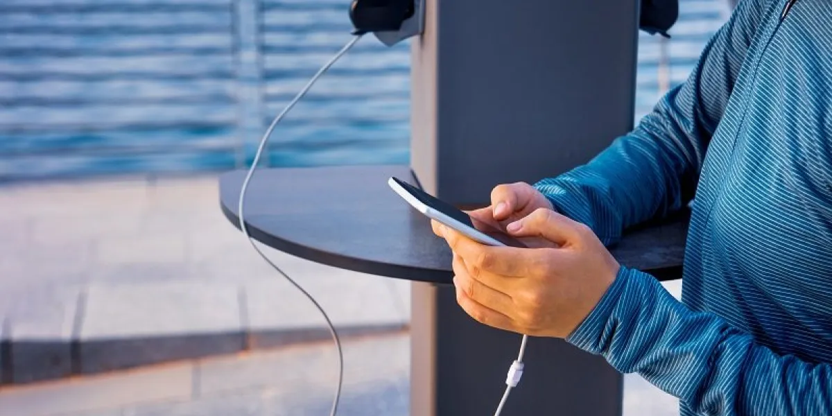 female using phone and charging on a public charger