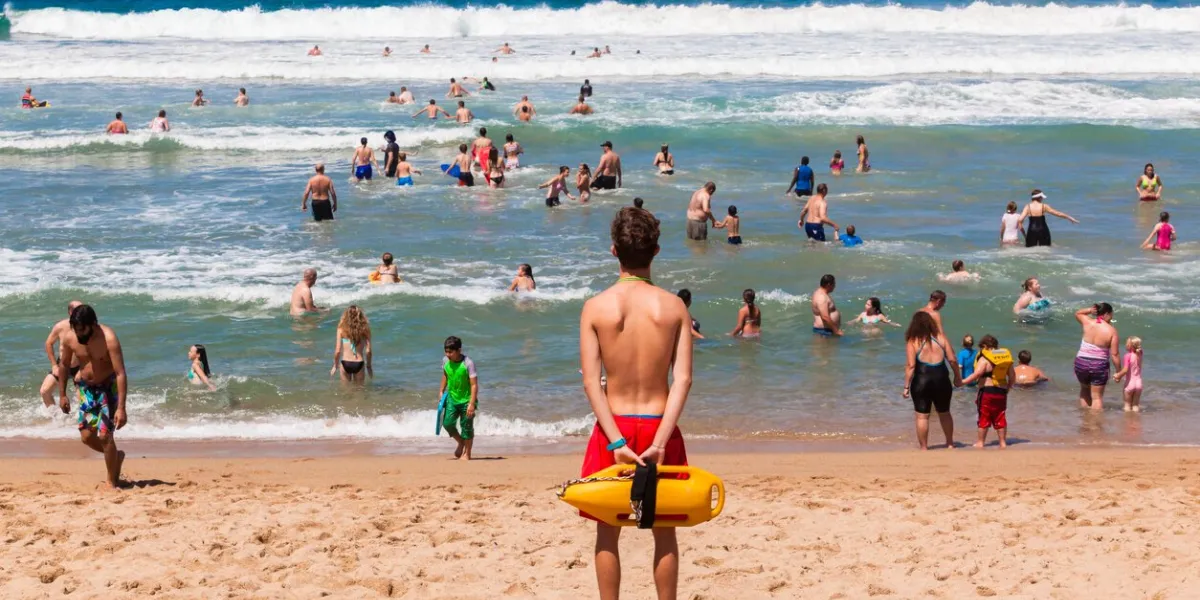 ramsgate south coast, south africa - october 4, 2015  lifeguard with safety rescue swimming buoy watching public swim in ocean waves