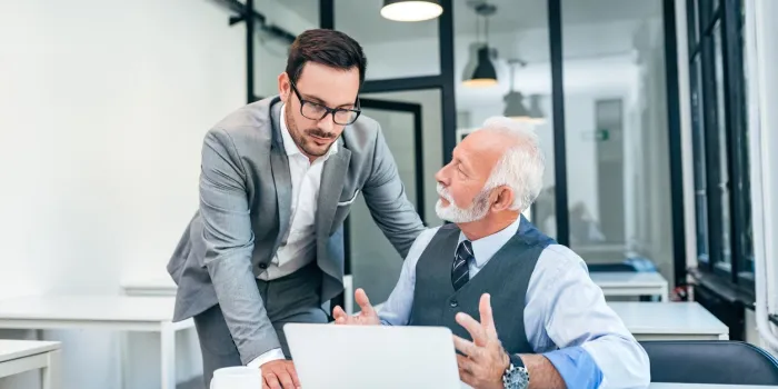 young man discussing with boss or older employee in modern office