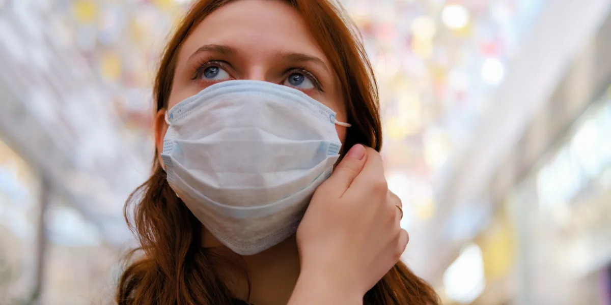 a young woman is considering whether to remove the medical mask after the end of the quarantine due to the coronavirus portrait of a girl after the flu virus epidemic, close-up